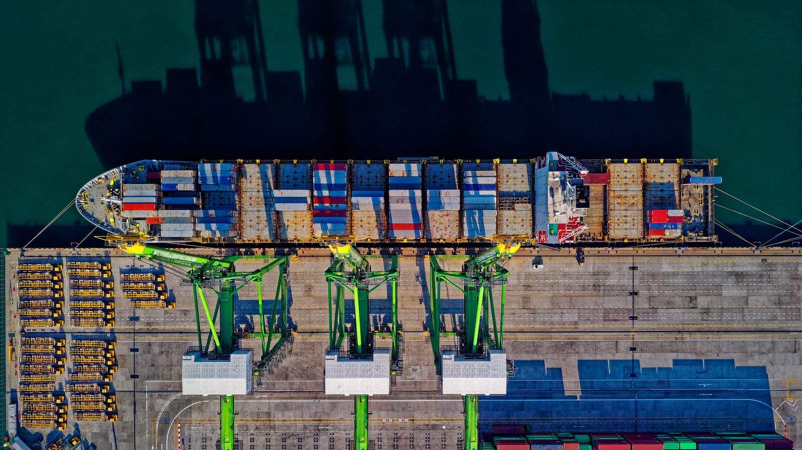 Aerial view of a container ship docked beside port cranes
