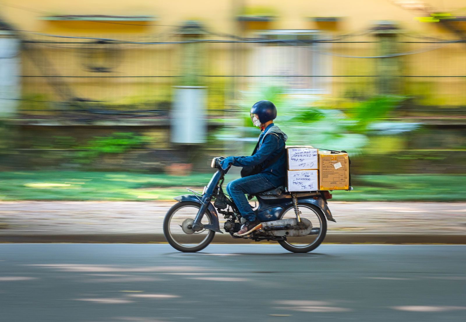 Courier riding a scooter with parcels strapped to the back