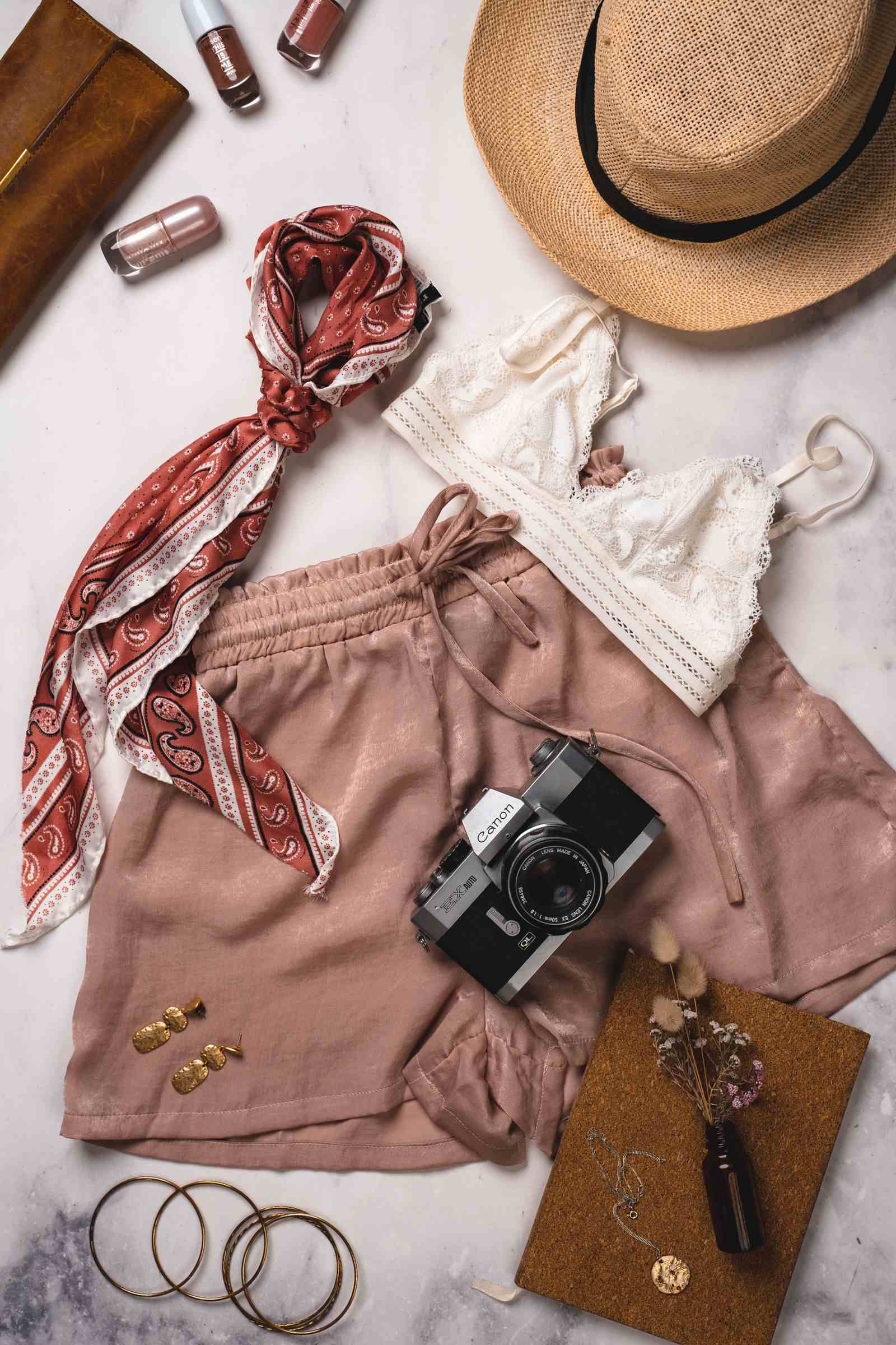 Flat lay of clothing, accessories and a film camera on marble