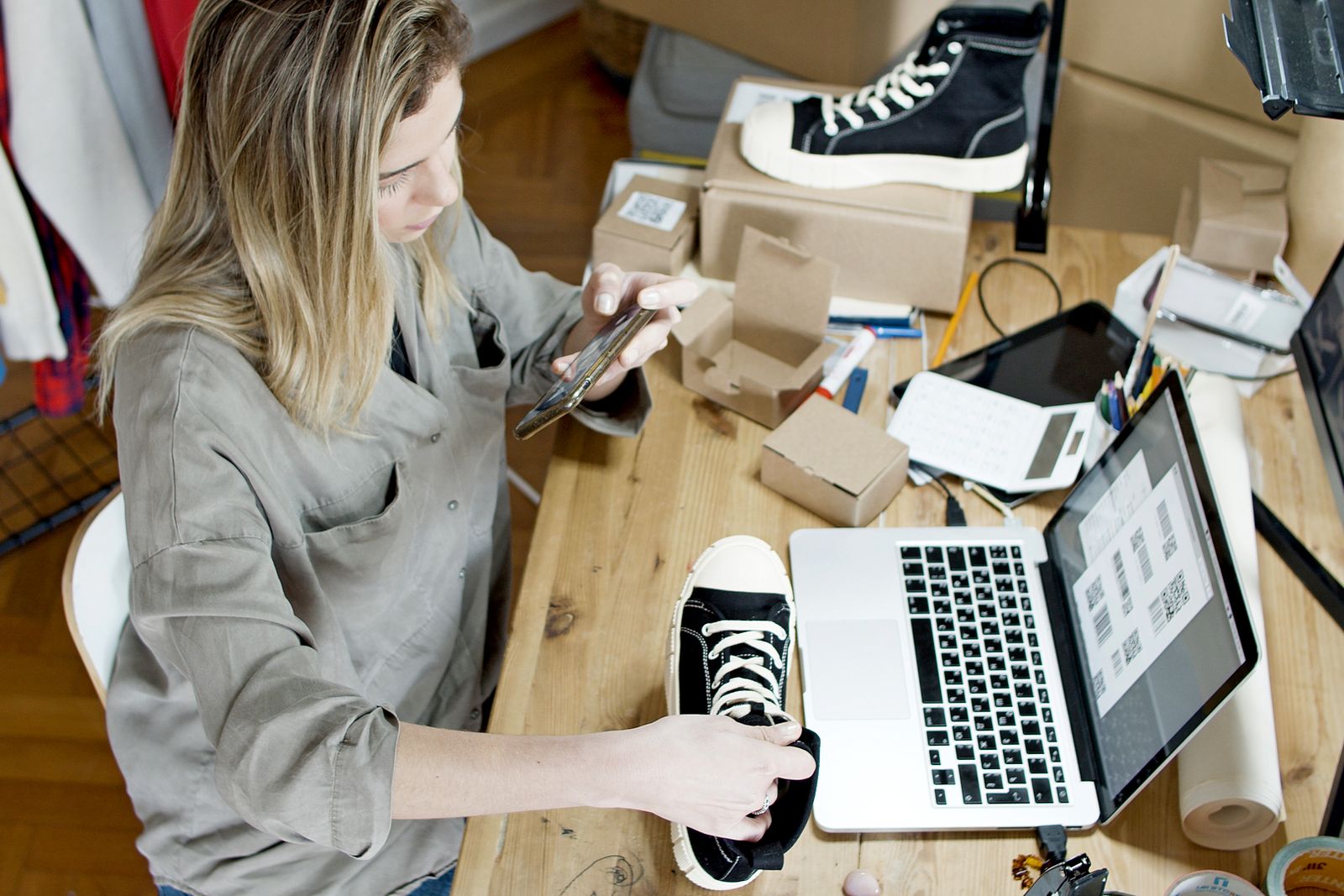 Ecommerce seller photographing products beside a laptop and parcels